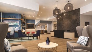 A modern lobby with a round coffee table, seating area, and a reception desk. - Hyatt Place Niagara Falls (Niagara Falls)