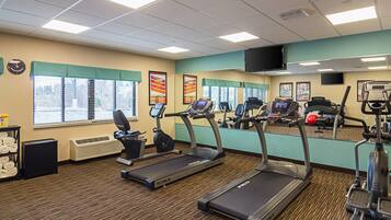 Une salle de sport équipée de tapis de course, de vélos d’exercice et d’une machine de musculation.