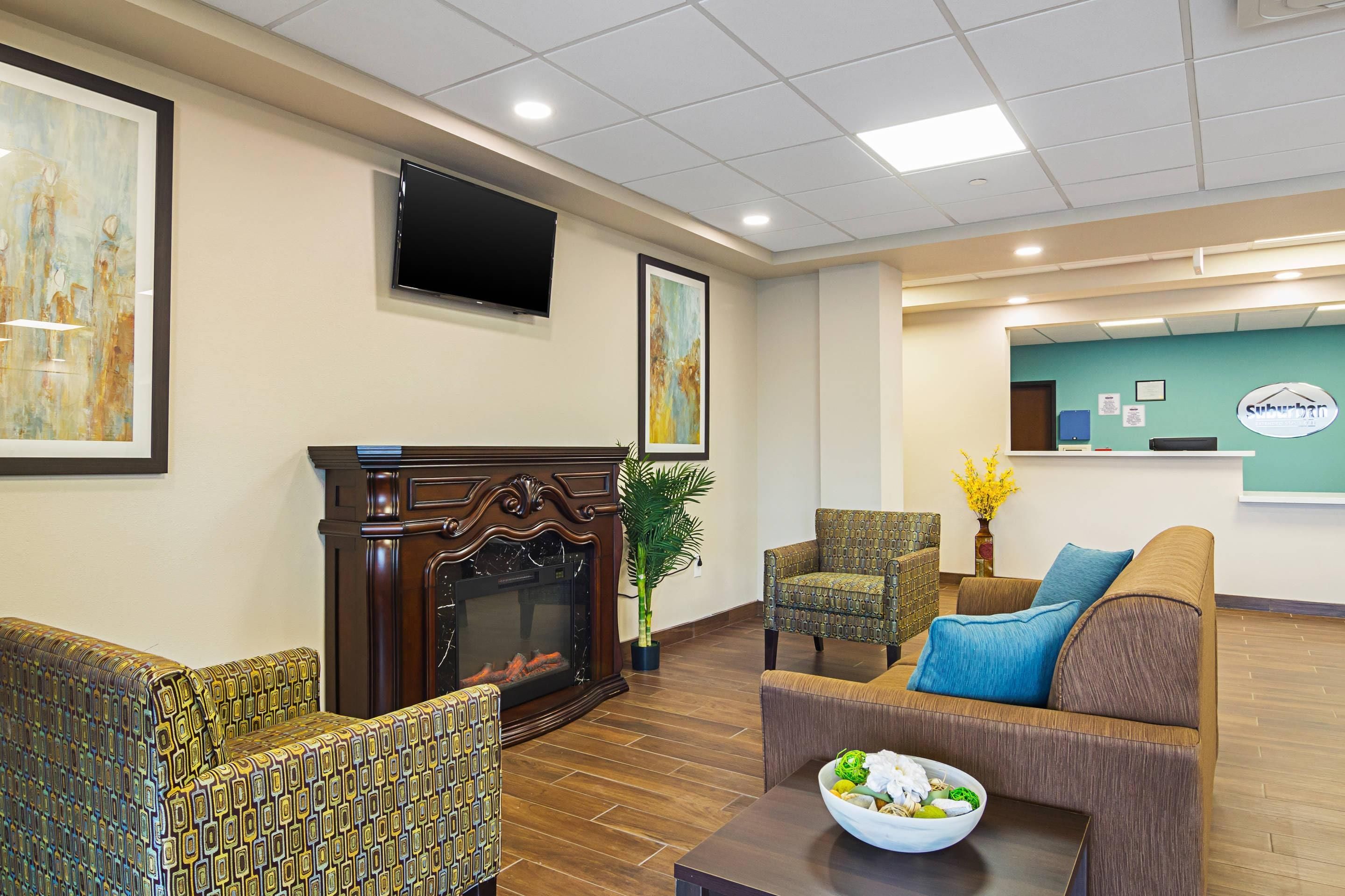 A hotel lobby with a fireplace, seating area, and a reception desk.