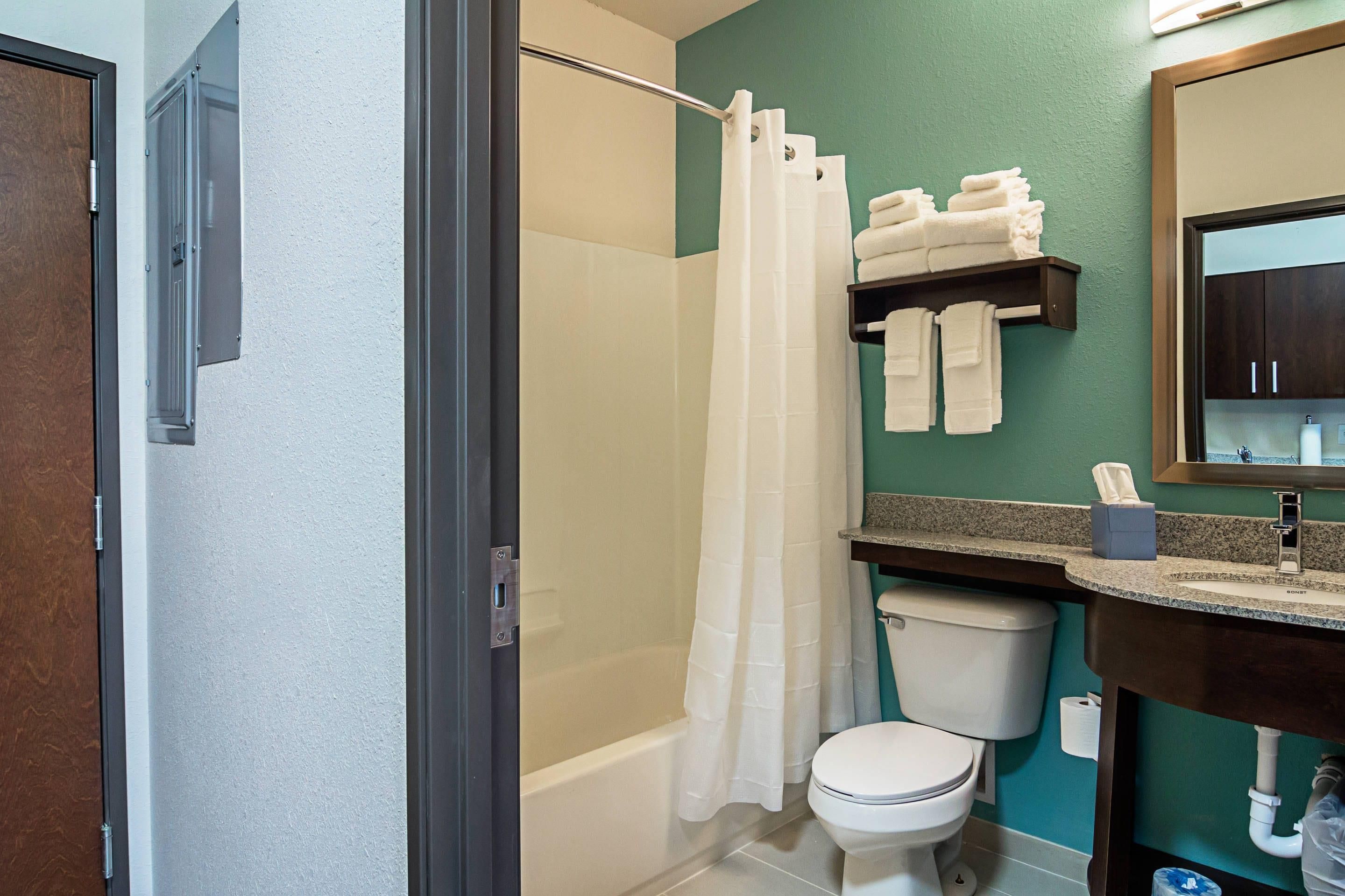 Une salle de bain équipée d’une douche, de toilettes et d’un porte-serviettes avec des serviettes pliées.