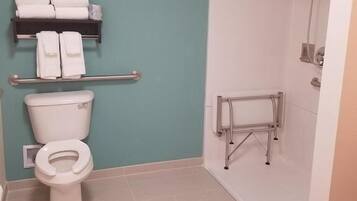 Un baño con inodoro, estante con toallas y zona de ducha.