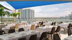 A rooftop dining area with tables set for guests, overlooking a cityscape. - Circ Hotel (Hollywood)