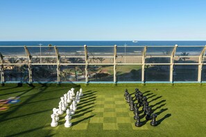 A chessboard on artificial grass with a view of the beach and ocean through a glass enclosure. - Durban Spa (Durban)