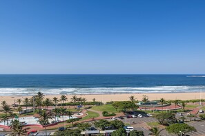 A coastal view with a beach, palm trees, and a parking area. - Durban Spa (Durban)