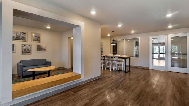 A spacious living area with a sofa, coffee table, and dining table with chairs. - Extended Stay America Select Suites Tampa Brandon East (Tampa)
