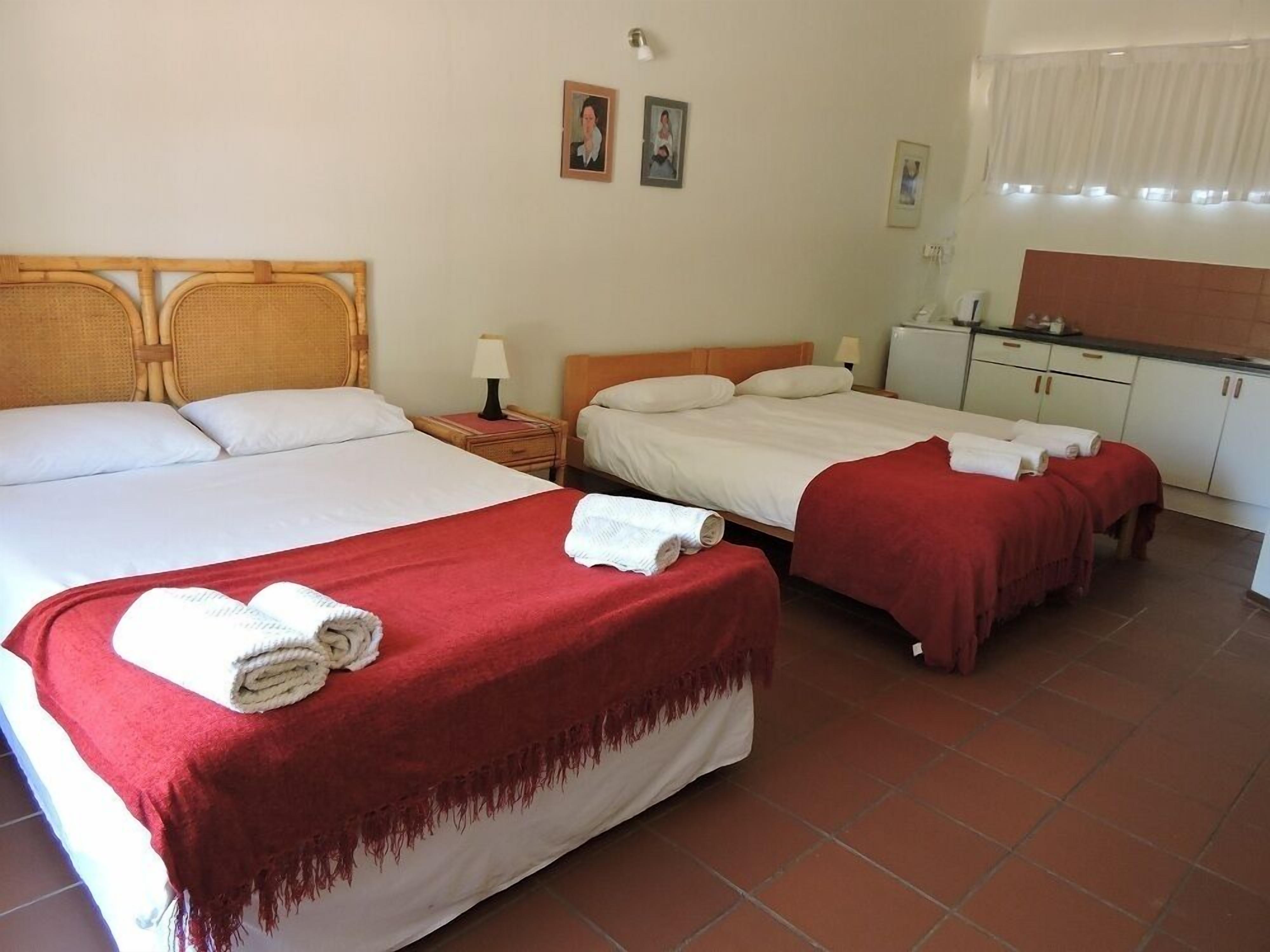 Habitación de hotel con dos camas, kitchenette pequeña y baño.