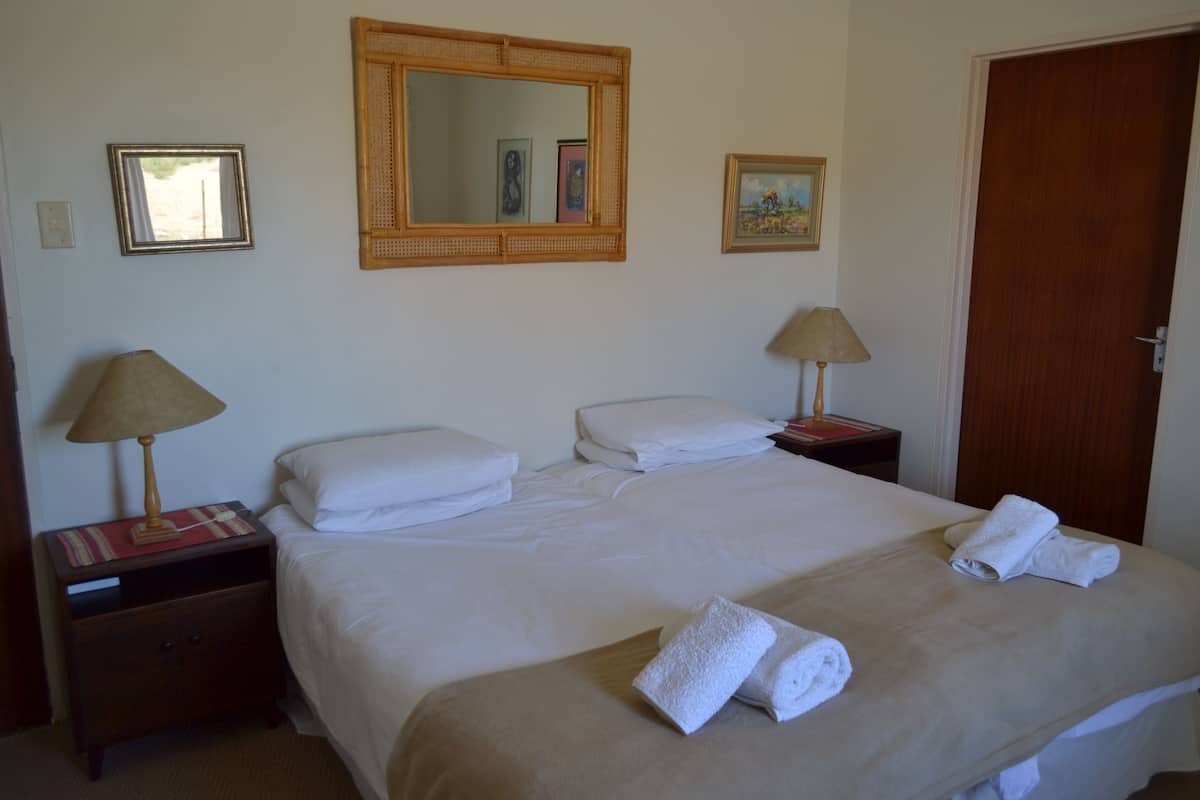 A hotel room with a large bed, two bedside tables with lamps, a mirror, and a door.