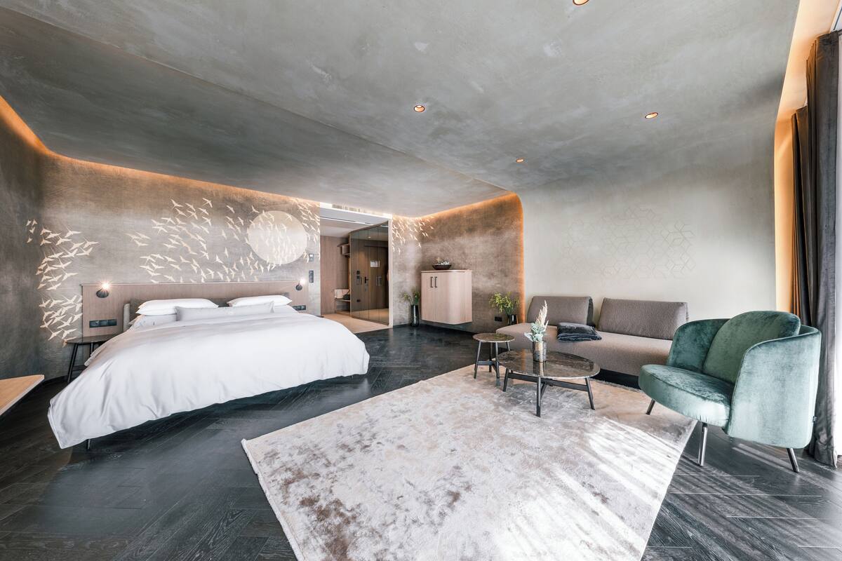 Une chambre moderne avec un grand lit, un canapé, une table basse et un fauteuil vert.