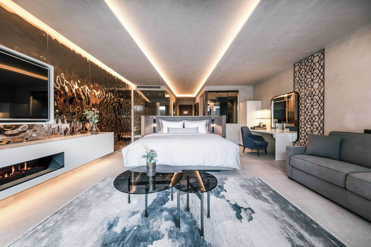 Une chambre moderne avec un grand lit, une télévision, une cheminée et un canapé.