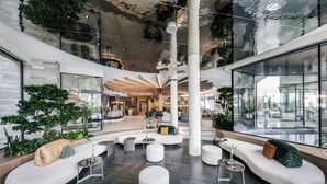 Un hall d’entrée spacieux, doté de mobilier moderne, de grandes fenêtres et de plantes d’intérieur.