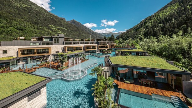 A modern hotel with a large outdoor pool, multiple swimming areas, and a rooftop garden. - Quellenhof See Lodge (San Martino in Passiria)