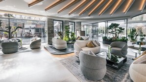 A modern interior with a curved seating area, large windows, and indoor plants. - Quellenhof See Lodge (San Martino in Passiria)