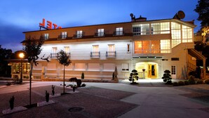 A hotel with a modern facade, multiple balconies, and a well-lit entrance. - Hotel A Queimada (A Estrada)