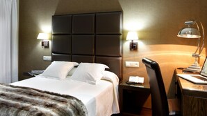 A hotel room with a large bed, a desk with a laptop, a chair, and two bedside lamps. - Hotel A Queimada (A Estrada)