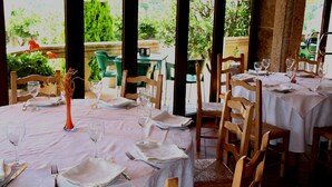 A dining area with tables set for four, each with a vase of dried flowers, wine glasses, and cutlery. - Hotel A Queimada (A Estrada)