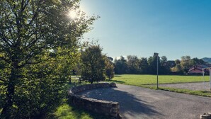 A paved driveway with a stone wall, surrounded by lush greenery and trees. - Albergo Villa Priula (Sorisole)