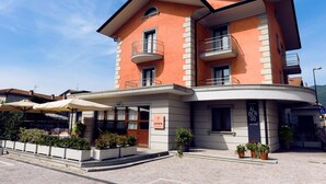 A multi-story hotel with a curved facade, outdoor seating area, and potted plants. - Albergo Villa Priula (Sorisole)