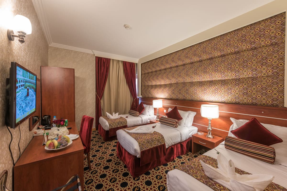 Ein Hotelzimmer mit zwei Betten, einem Fernseher, einem Schreibtisch mit einem Laptop und einer Wand mit Muster.