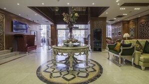 Eine Lobby mit Marmorboden, einem aufwendig gestalteten Tisch in der Mitte und einer Couch.