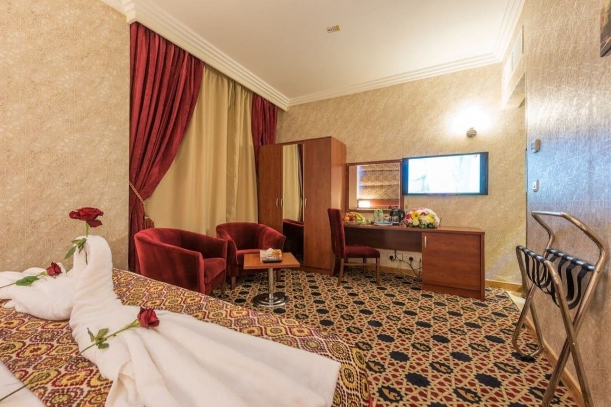 Ein Hotelzimmer mit Bett, Schreibtisch, Sessel und Fernseher.
