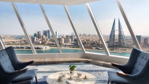 A high-rise room with a panoramic view of a city skyline and a body of water. - Wyndham Grand Manama (Manama)