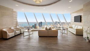A spacious living room with a city view, a chandelier, and a modern sofa. - Wyndham Grand Manama (Manama)
