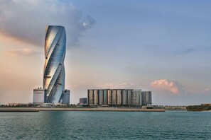 A modern building with a unique twisted design, situated near a body of water. - Wyndham Grand Manama (Manama)