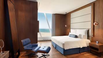 Una camera d'hotel moderna con un grande letto, una scrivania, una sedia e vista sul mare.