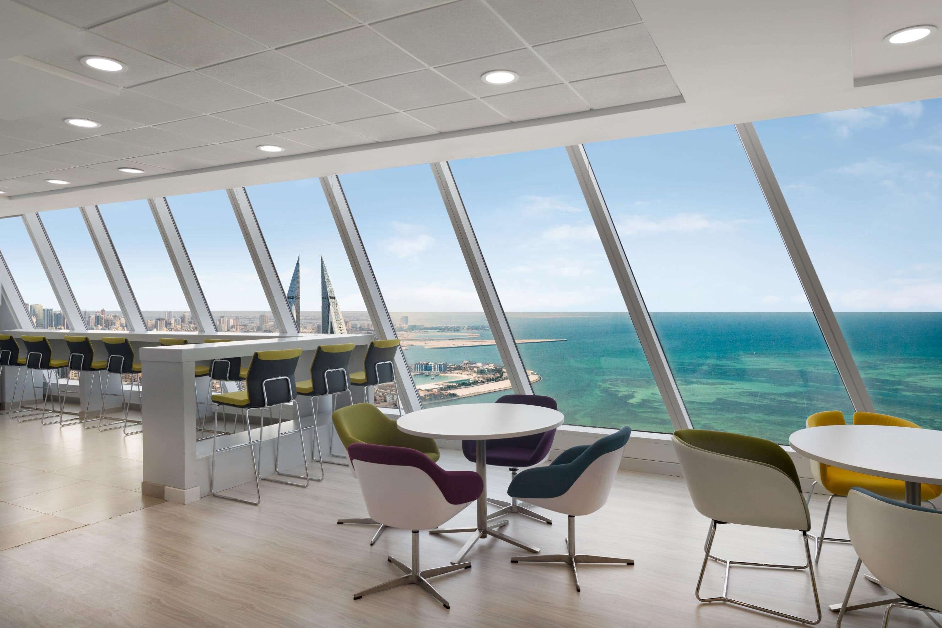 A modern dining area with a view of the ocean and city skyline.