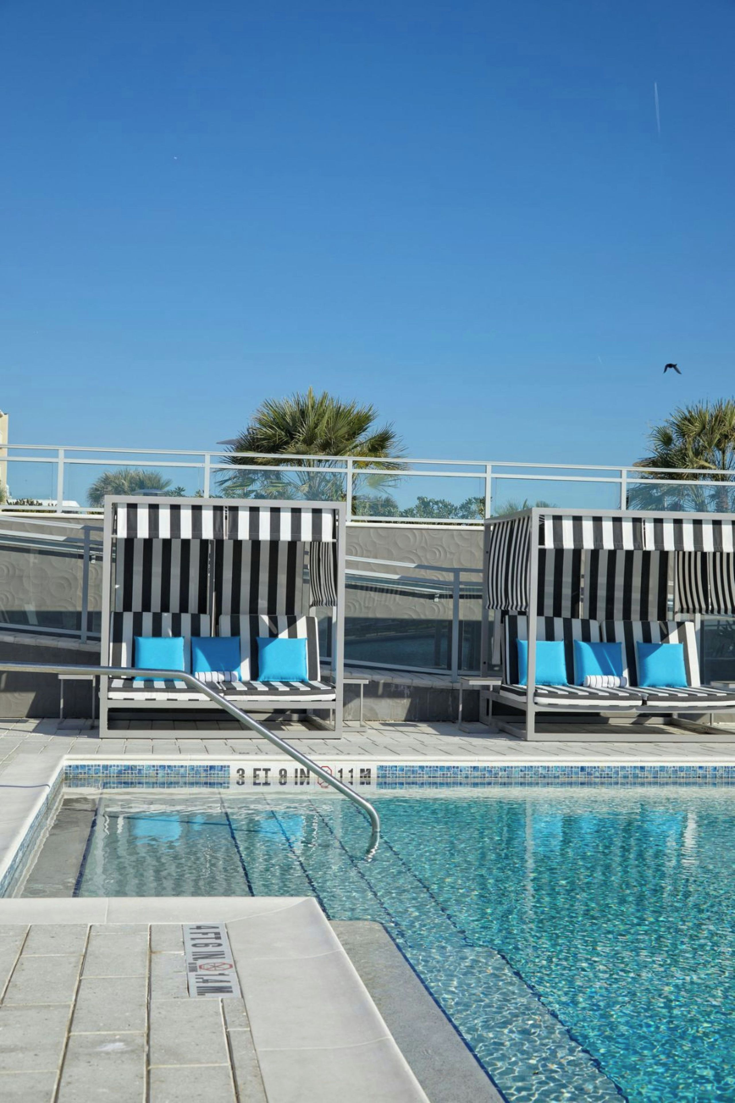 A pool area with lounge chairs and a clear blue sky.