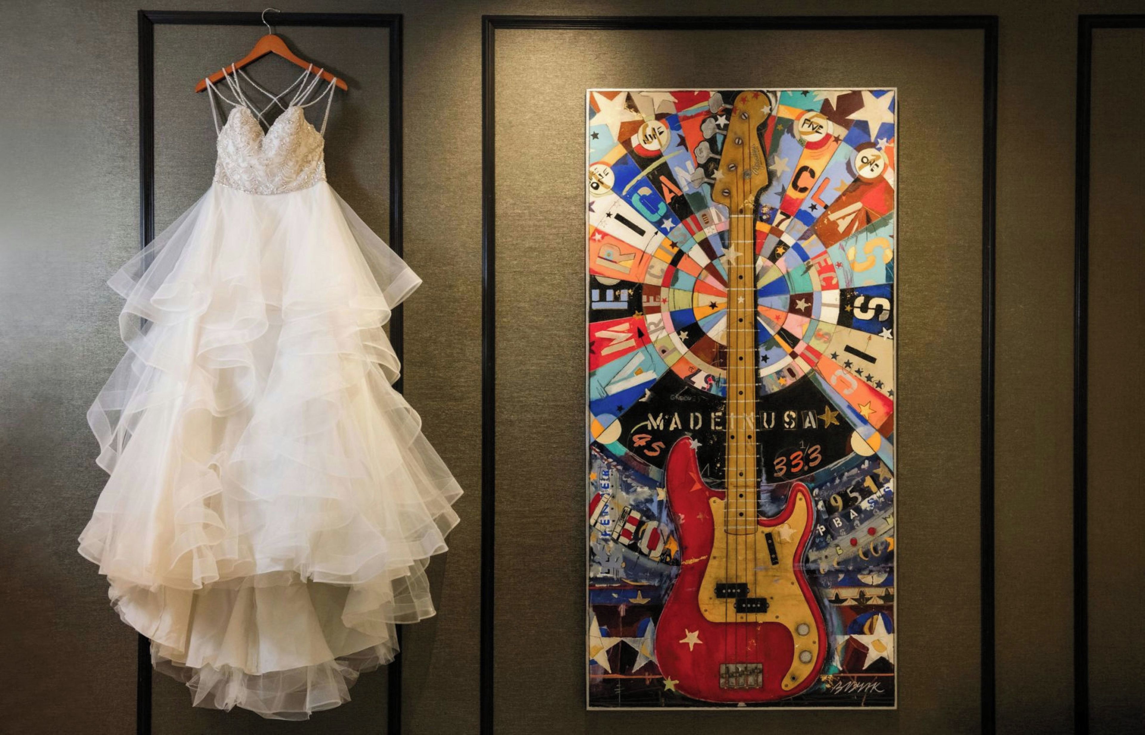 A wedding dress and a guitar poster on a wall.