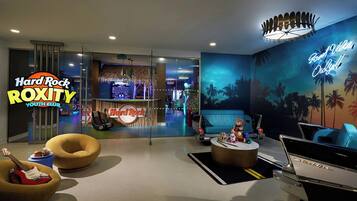 A Hard Rock Roxy Youth Club with a tropical mural, a neon sign, a vintage car, and a guitar-shaped chair.