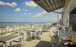 An outdoor seating area with tables and chairs, overlooking a beach. - Hard Rock Hotel Daytona Beach (Daytona Beach)
