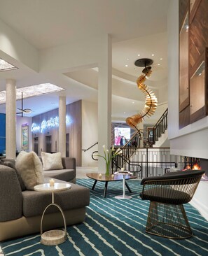 Un hall espacioso con una escalera moderna, un sofá, una mesa de centro y un original candelabro en espiral.