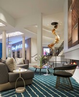 A spacious lobby with a modern staircase, a sofa, a coffee table, and a decorative spiral light fixture.