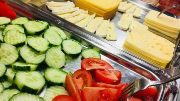 A buffet with various food items including sliced cucumbers, tomatoes, cheese, and meats.