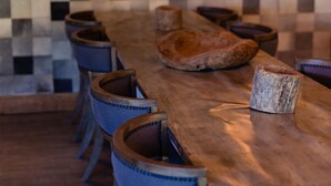 A long wooden table with blue upholstered chairs, a checkered wall, and two wall-mounted lamps. - Greenhorn Ranch (Quincy)