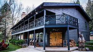A two-story building with a balcony, wooden door, and outdoor seating area. - Greenhorn Ranch (Quincy)