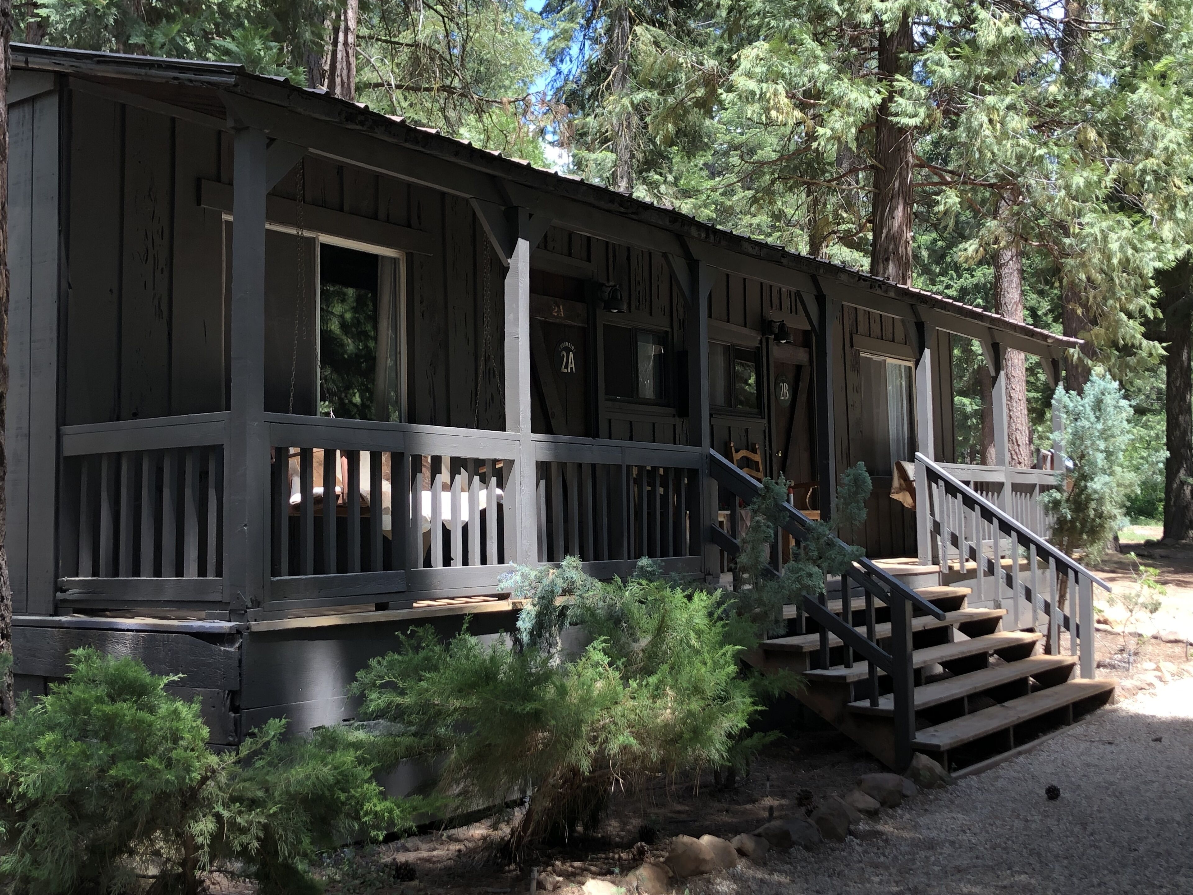 A rustic cabin with a wooden deck and a staircase leading to the entrance.