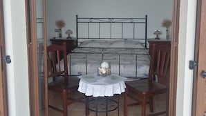 A bedroom with a bed, two wooden chairs, a small round table, and a ceiling light. - I Tufi (Colonnella)