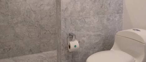 A bathroom with a toilet, a shower, and marble walls.