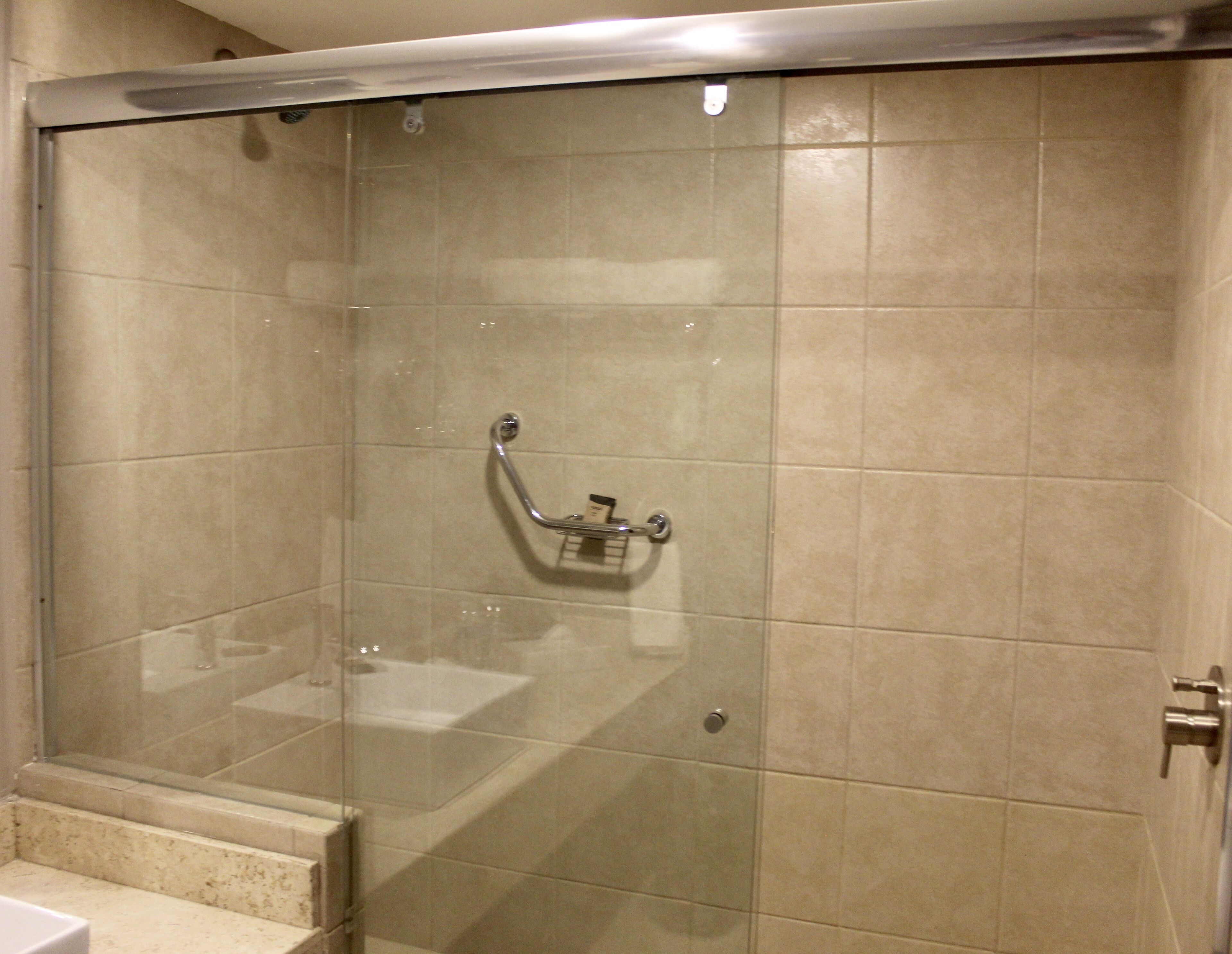 A walk-in shower with a glass door, a handheld showerhead, and a towel rack.