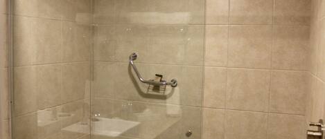 A walk-in shower with a glass door, a handheld showerhead, and a towel rack.