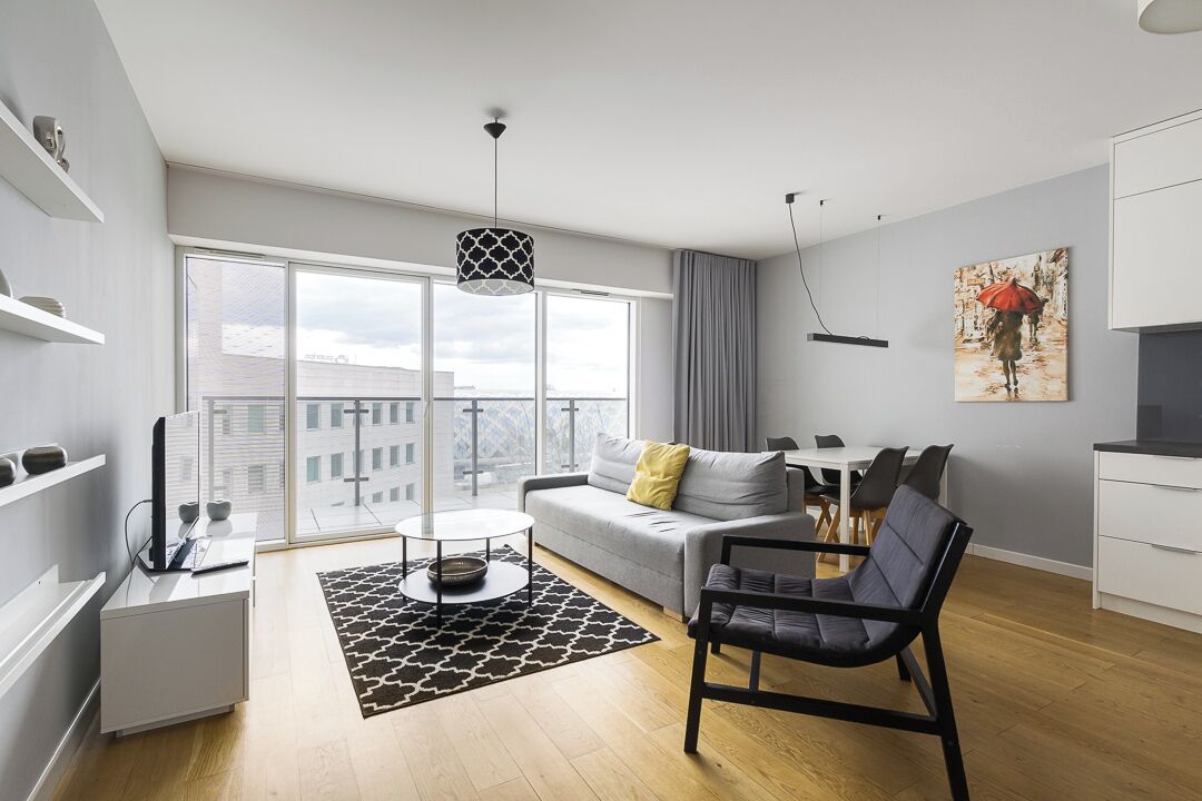 A modern living room with a sofa, a black chair, a coffee table, and a painting on the wall.