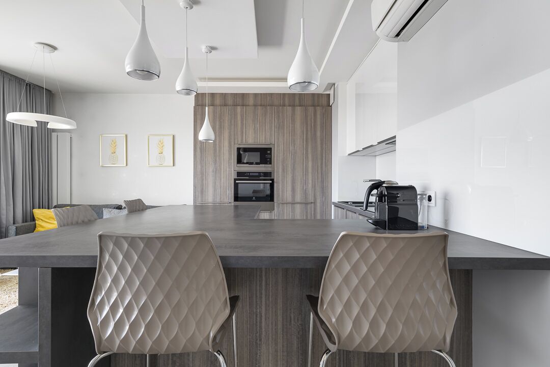 Een moderne keuken met een centraal eiland, hanglampen en een magnetron.