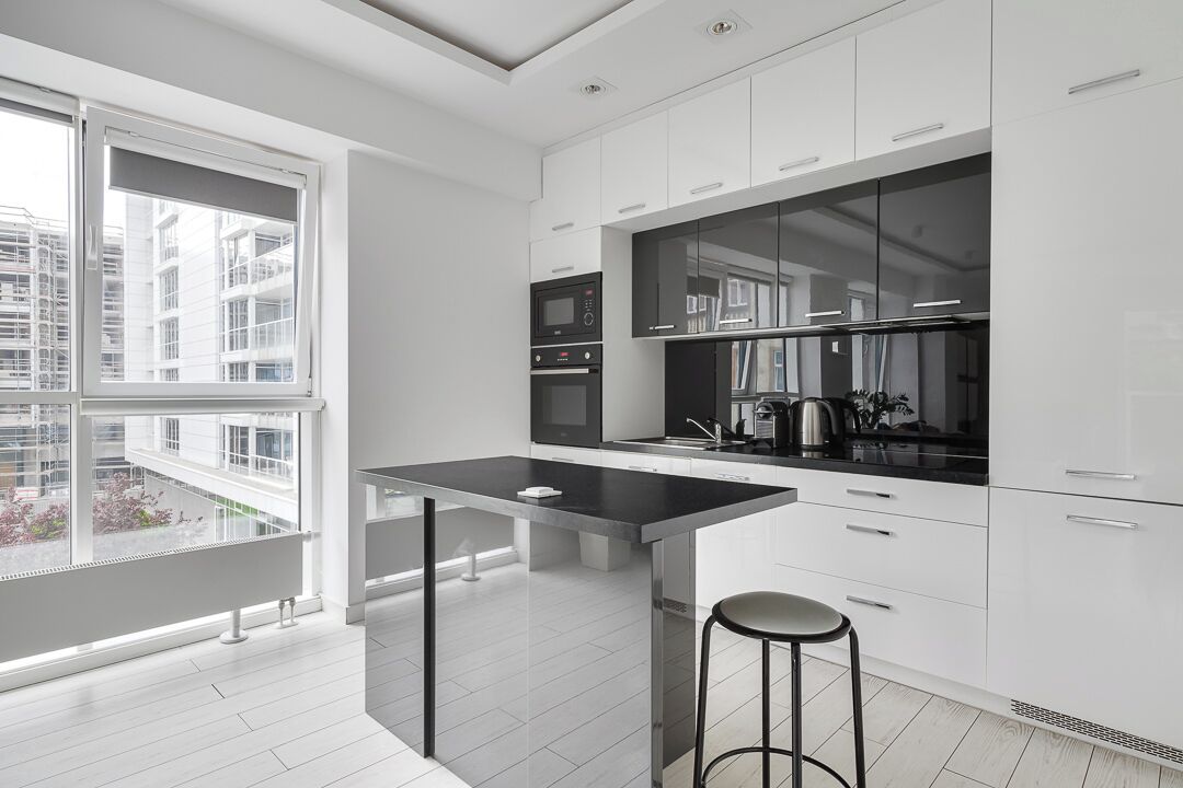 A modern kitchen with a large window, white cabinetry, and a central island.