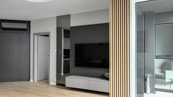 Un moderno salón con televisor de pantalla plana, mueble empotrado de entretenimiento y puerta corredera de vidrio que da a un balcón.