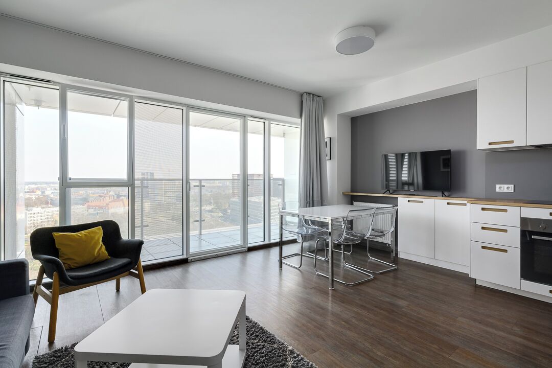 A modern apartment with a large balcony, a dining area, and a kitchen.