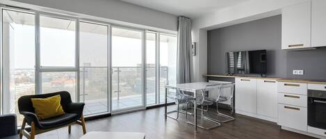 A modern apartment with a large balcony, a dining area, and a kitchen.
