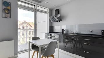 A modern kitchen with a dining area, large windows, and a view of buildings outside.